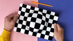 a person holding a piece of paper with a black and white checkerboard design on it