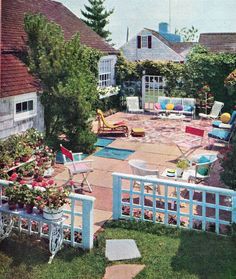 an aerial view of a backyard with chairs and flowers in the foreground, surrounded by greenery