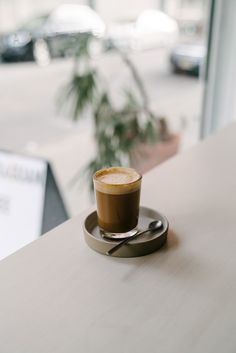 a cappuccino sitting on top of a wooden table next to a window