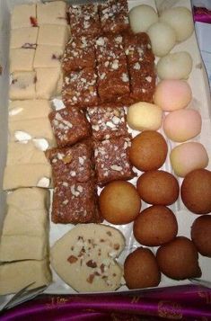 there are many different types of desserts in the box on the table, including brownies and other pastries