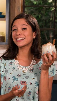 a woman holding a drink and smiling at the camera