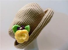 a crocheted hat with a flower on the brim is sitting on a mannequin head