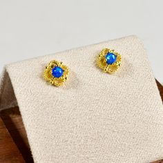 Elevate your elegance with our Imitation Blue Opal Mini Studs. Each earring features a captivating blue opal inlaid in a delicate, 14k gold plated hollow flower setting. The opal's vibrant hues shimmer beautifully, creating a mesmerizing contrast against the golden petals.  Perfect for adding a subtle yet sophisticated touch to any outfit, these mini studs are lightweight and comfortable for all-day wear. Ideal for those who appreciate timeless beauty and refined craftsmanship, these earrings ar Blue Gold-plated Earrings For Wedding, Blue Round Gold-plated Earrings, Blue Round Gold Plated Earrings, Formal Blue Gold-plated Earrings, Blue 14k Gold Earrings For Wedding, Flower Setting, Blue Gemstone Earrings, Mini Studs, Blue Gemstones