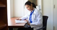 a female doctor sitting at a desk reading a book