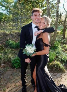 a man in a tuxedo hugging a woman in a black dress