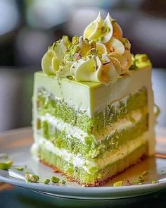 a piece of green cake on a plate with pistachios and white frosting