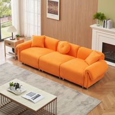 an orange couch sitting on top of a hard wood floor next to a fire place