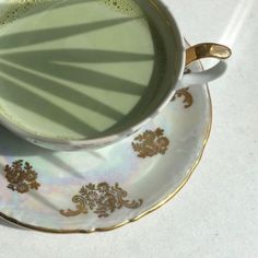 a coffee cup and saucer on a white table with shadows from the sun coming in