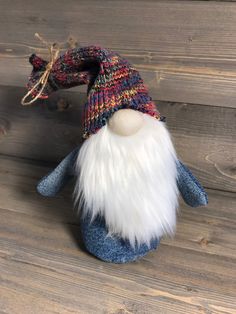 a small stuffed animal wearing a knitted hat on top of a wooden floor next to a wall