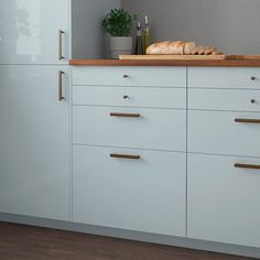 a kitchen with white cabinets and wooden counter tops, along with a loaf of bread on the counter