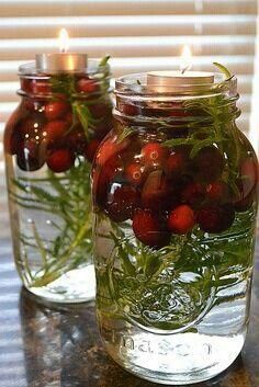 two mason jars filled with strawberries and greenery