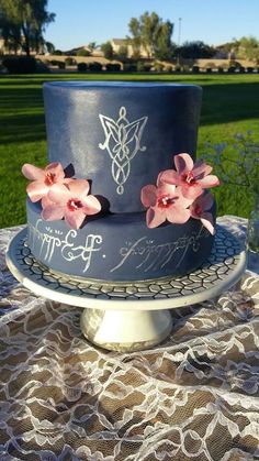 a blue cake with pink flowers on it sitting on top of a doily covered table