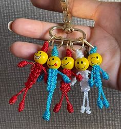 a person holding three smiley face key chains in their hand, with the other two smiling faces attached to them