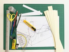 some construction supplies are laying out on a cutting board with scissors, tape and pencils