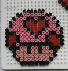 this is an image of a beaded skull on a white board with red and black beads