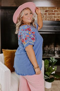 - Take a beachside stroll in this beautiful top! - Unlined material - A wide round neckline - Short sleeves featuring colorful floral embroidery with unfinished frayed cuffs - A relaxed silhouette that ends in a rounded hemline with frayed detail Blue Short Sleeve Top With Frayed Hem, Beach Blue Tops With Tassels, Blue Beach Tops With Tassels, Blue Tassel Tops For Beach, Bohemian Blue Top With Tassels, Bohemian Tops With Embroidered Sleeves For Vacation, Spring Beach Embroidered Blue Top, Spring Blue Embroidered Top For Beach, Blue Embroidered Short Sleeve Top For Vacation