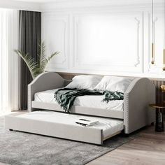 a white day bed sitting on top of a wooden floor