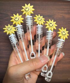 a person holding five plastic toothbrushes with smiley faces on them