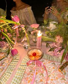 two women sitting at a table with flowers and candles