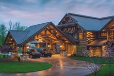 a large log home with lots of windows and lights on it's front porch