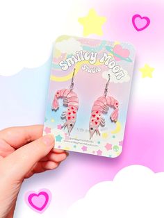 a pair of pink fish shaped earrings with polka dots on the bottom and stars in the background