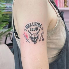 a woman with a tattoo on her arm that says hellfire club