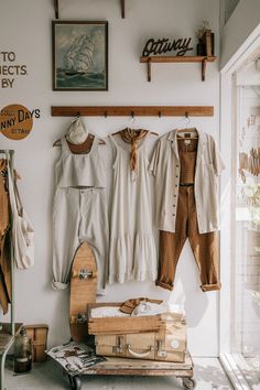 an assortment of clothing hanging on the wall next to a suitcase and other items in front of a window