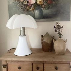 a white lamp sitting on top of a wooden table next to a vase filled with flowers