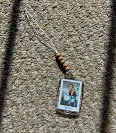 a necklace with a photo hanging from it's side on a carpeted surface