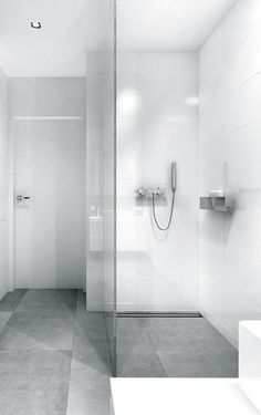 a bathroom with a glass shower door and white walls, along with a tiled floor