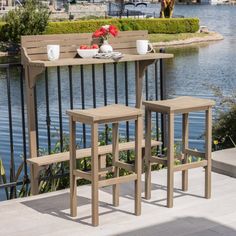 two wooden stools sitting next to each other near a lake