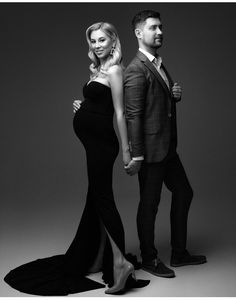 a man and woman standing next to each other in black dress clothes, posing for the camera