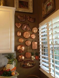 there are many plates on the wall above the sink and in the window sill