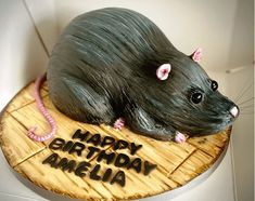 a birthday cake made to look like a rat sitting on top of a wooden board