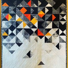 a quilted wall hanging with an orange and black geometric design on it's side