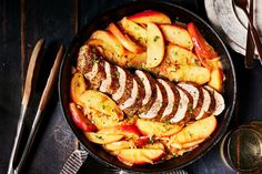 a pan filled with meat and vegetables on top of a wooden table next to utensils