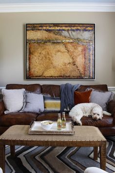 a living room with a dog laying on the couch and a painting hanging above it