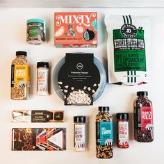 an assortment of food items laid out on top of a white surface, including popcorn, nuts, and spices