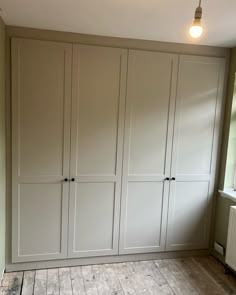 an empty room with white cupboards and wood flooring