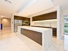 a large kitchen with marble counter tops and wooden cabinets, along with an island in the middle