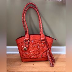 This Shoulder Bag Is A Stunner! Beautiful Tooled Leather With Gold Leather Backing. It’s A Lovely Orange Color That Is Just Perfect For Fall And Look At Those Tassels!! The Double Braided Handles Rest Comfortably On The Shoulder. It’s Spacious With A Main Zip Top Compartment And Has 2 Side Pockets, One On Each Side Of The Main Compartment. 100% Leather Pockets, Pockets, Pockets Inside Rear Zip Pocket And 2 Slip Pockets Gold Hardware Faux Suede Lining Key Clip 12”W X 10.5”H X 4”D Orange Shoulder Bag For Everyday Use, Orange Satchel With Handle Drop For Everyday Use, Orange Satchel Shoulder Bag With Handle Drop, Orange Leather Handheld Shoulder Bag, Key Clip, Tooled Leather, Orange Gold, Gold Leather, Leather Tooling