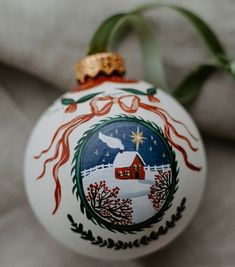 a white ornament with a red house on it