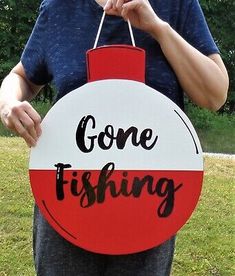 a man holding a sign that says gone fishing in black and red letters on it