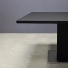 a black table sitting on top of a white floor next to a gray wall in an empty room