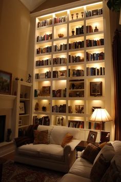 a living room filled with lots of white furniture and bookshelves full of books