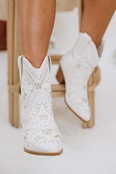 a close up of a person's legs wearing white cowboy boots and high heels