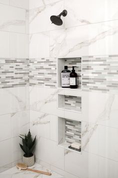 a white tiled bathroom with shelves holding personal care products and a succulent plant