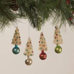 three christmas ornaments hanging from a pine tree with red, green and blue baubles