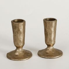 two gold colored candlesticks sitting next to each other