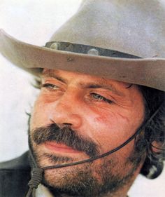 a close up of a person wearing a hat with a moustache on his face